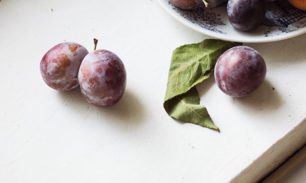 red and purple grapes on white ceramic bowl