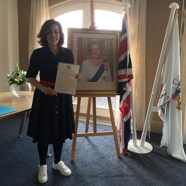 Vicky Teinaki with a picture of the queen and a citizenship certificate